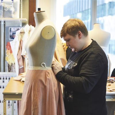 Costume student pinning a dress on a mannequin